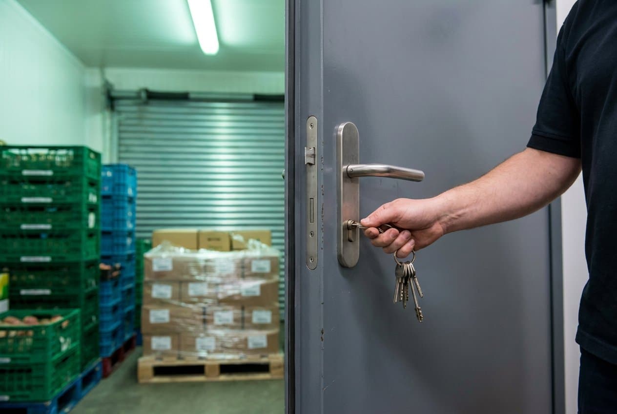 Staff member unlocking a back-of-house door in a supermarket storeroom